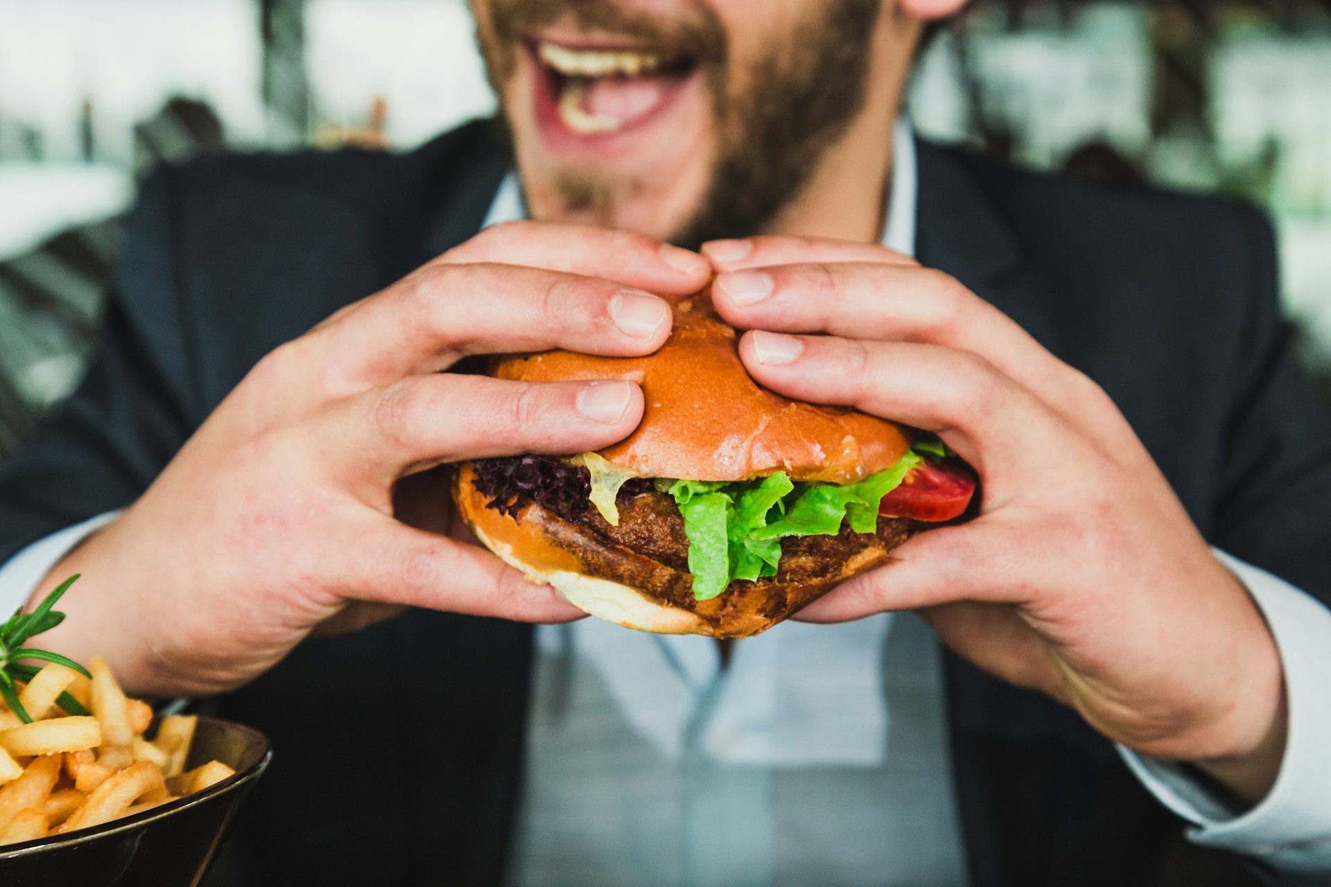 Man som håller en hamburgare. Foto: Sander Dalhuisen/Unsplash